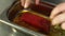 The cook turns over a piece of raw tuna in a bowl of marinade.close-up