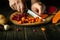 A cook uses a knife to cut boiled carrots to prepare a vegetable dish on the kitchen table. Venaigret cooking concept on dark