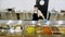 A cook or waiter, in protective gloves and mask, stands behind display case with different dishes, in self-service