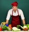 Cook works in kitchen near table with vegetables and tools