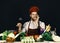 Cook works in kitchen near vegetables and tools. Italian drink and sommelier concept. Man in hat and apron