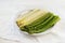 Cooked asparagus, green and white on a plate, white table with n