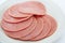 Cooked boiled ham sausage or rolled bologna slices on a white plate