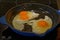 A cooked breakfast has the surprise of a double-yolked egg, breakfast being cooked in a cast iron pan