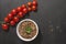 Cooked buckwheat porridge in a deep plate on a black wooden background with cherry tomatoes. Copy space Top view