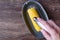 Cooked and buttered corn on the cob on a gray dish, womanâ€™s hand shaking salt