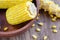 Cooked corncobs on a dark wooden plate,