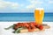 Cooked crayfishes served with beer on white wooden table near sea