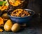 Cooked forest Mushrooms in rustic bowl and potato on dark rustic background, front view. Autumn cooking