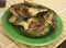 Cooked fried halves artichokes on green plate