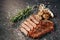 Cooked halved and sliced grilled piece of juicy meat sitting on a sprinkling of salt and pepper peas, next to a sprig of rosemary