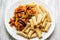 Cooked Italian tortiglioni pasta with turkey steak chop under vegetables and tomato paste