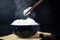 Cooked jasmine rice in ceramic cups and chopsticks holding hot jasmine rice. Placed on a black wooden table. Close up shot