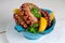 Cooked marinated octopus in a blue bowl on white background. Close up, top view.