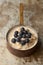 Cooked Oatmeal with Blueberries in Copper Saucepan on Weathered Stainless Steel Surface