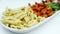 cooked pasta, chicken and fresh salad on a plate on white background