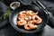 Cooked peeled king prawns, shrimps on a plate. Black background. Top view