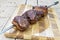 Cooked Picanha skewer ready to eat leaning on chopping board