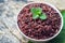Cooked purple rice berry in bowl over green leaf background
