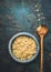 Cooked quinoa in bowl with cooking wooden spoon on dark rustic background, top view, place for text: recipes and menus, vertical.