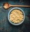 Cooked quinoa seeds in rustic bowl with wooden cooking spoon on dark vintage background, top view