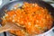 Cooked soup ingredient. Sauteed chopped onions and grated carrots for soup in a frying pan. fried vegetables