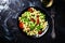 Cooked vegetarian pasta with broccoli and tomatoes, dark background, top view