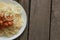 Cooked vermicelli with beans in tomato and onion in a white plate lies on a wooden old board