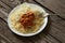 Cooked vermicelli with beans in tomato and onion in a white plate lies on a wooden old board