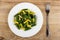 Cooked yellow and green beans in plate, fork on table. Top view