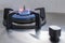 Cooker stove burner with grate and blue flame with stove knob.