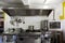 Cooker system from steel with stove, grill, oven and extractor hood in a professional canteen kitchen