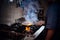 Cooker wearing gloves and apron frying flambe on a pan in a dark restaurant kitchen