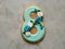 Cookie covered with blue glaze made in a form of number eight with flowers - cornflowers and daisies - on gray background. Ginger