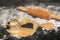 Cookie dough lies unrolled on a dark countertop. Flour is next to it and a rolling pin. A heart shape is on the dough, a heart has