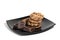 Cookies and chocolate pieces on black plate, isolated on white