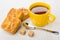 Cookies with marzipan, yellow cup with tea, teaspoon, sugar cube