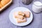 Cookies with powdered sugar on a white plate. In the background a basket of cookies and a cup of milk.