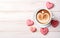 cookies shape heart with red and pink cream and coffee cup on white wooden table top view