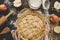 Cooking apple pie. Hands holding apple pie ready to be baked. Apple pie ingredients on wooden table