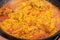 Cooking authentic Spanish Valencian paella with seafood chicken meat vegetables rice spices on large skillet