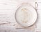 Cooking background with empty light plate and linen napkin on white wooden table
