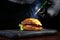 Cooking a big burger. The chef fries a piece of cheese with a gas burner.Unrecognizable photo on a black backgroundCheese being