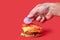 Cooking a big Burger. Hand rings of onion on the tomatoes. Red background.
