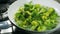 Cooking broccoli and green beans in a frying pan. Opening the lid.