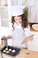 Cooking buns. Girl with tablet in kitchen. Light wooden background