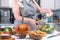 Cooking Caesar salad. Cook adds grated parmesan to glass bowl with salad in a home kitchen