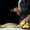 Cooking the chief of fresh fish, the chef salt fish on a black background with lemons, limes