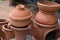 A cooking clay pot with covering lid on top with a another large cooking clay pot on a double clay stove