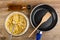 Cooking of corn pancakes. Bottle of oil. Fork in bowl with dough, food turner in frying pan on table. Top view